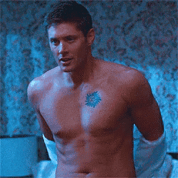 a shirtless man with a tattoo on his chest is laying in bed .