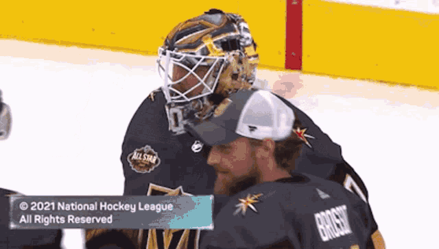 a hockey player wearing a helmet is talking to another hockey player