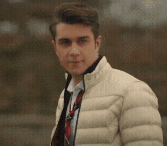 a young man wearing a white jacket and a red tie