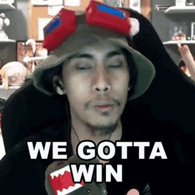 a man wearing a hat and goggles is saying `` we gotta win '' while sitting in a chair .