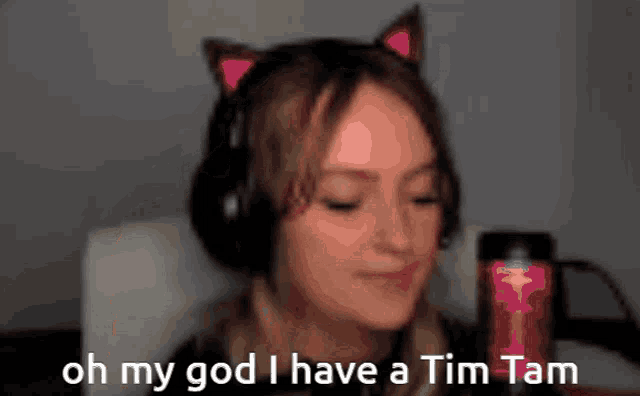 a woman wearing cat ears and headphones says " oh my god i have a tim tam "