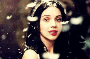 a close up of a woman 's face with feathers falling from her hair .