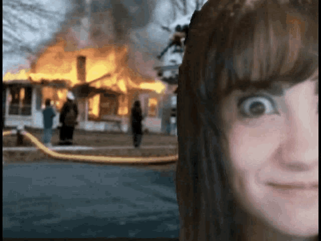a woman 's face is visible in front of a burning house