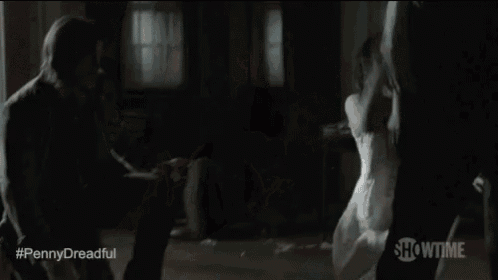 a woman is screaming at a man in a dark room while a man is holding her .