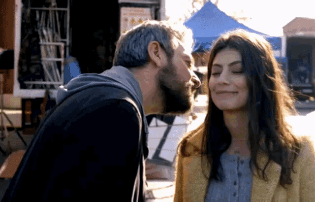 a man with a beard kisses a woman on the forehead