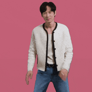 a man wearing a white cardigan and blue jeans is dancing on a pink background