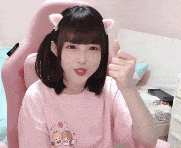 a girl wearing a pink shirt with a picture of two dogs on it giving a thumbs up