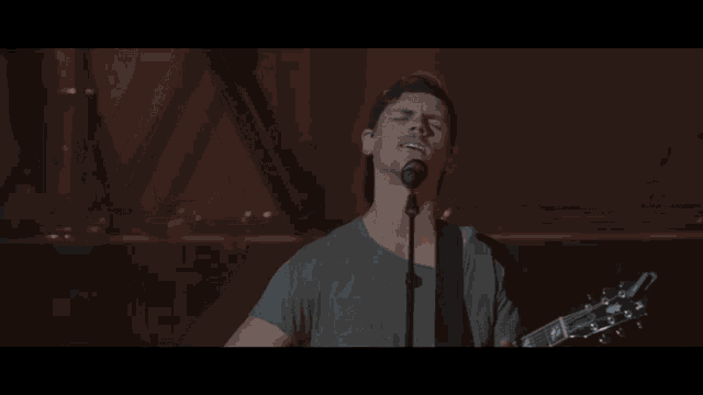 a man is singing into a microphone while playing a guitar