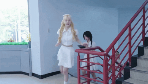 a woman in a white dress is walking down stairs