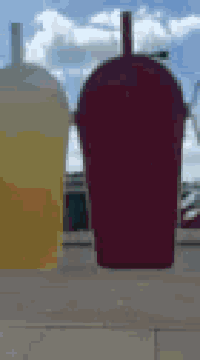 two cups of drinks are sitting on a sidewalk .