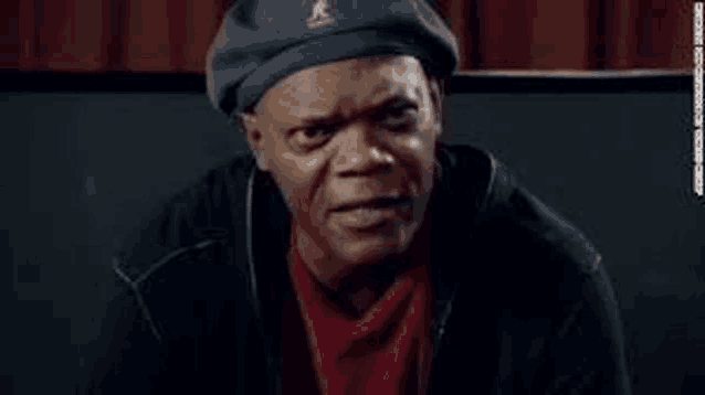 a man wearing a beret and a red shirt is making a face .