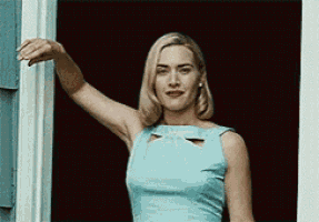 a woman in a light blue dress is standing in front of a window .