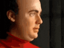 a close up of a man 's face wearing a red sweater .
