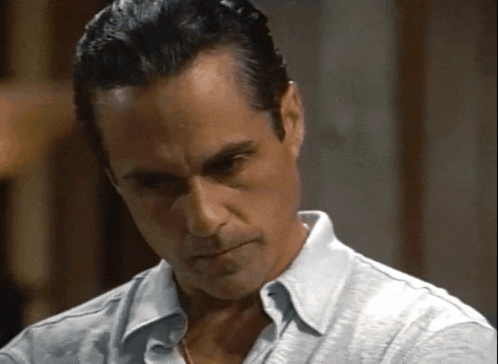 a man in a white shirt is looking down with a serious look on his face