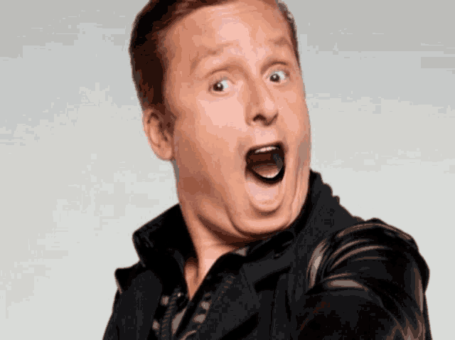 a man in a black jacket making a funny face with his mouth open