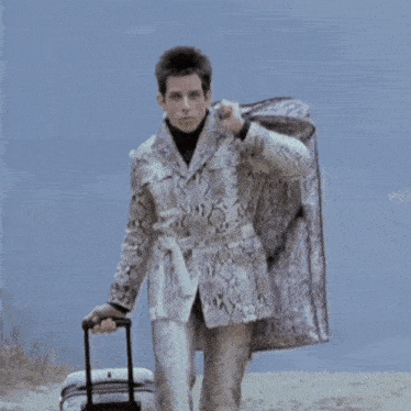 a man in a snakeskin suit is walking with a suitcase