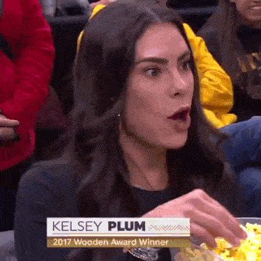 a woman named kelsey plum is eating popcorn in a crowd
