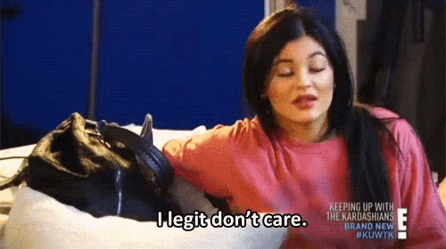 a woman in a pink shirt is holding a black purse and saying i legit do n't care .
