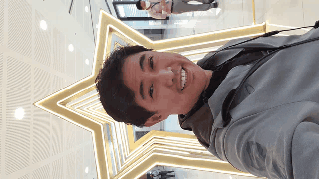 a man in a suit smiles in front of a large star