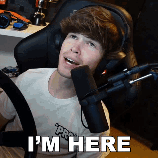 a man sitting in front of a microphone with the words " i 'm here " below him