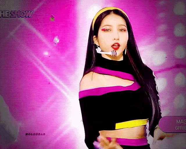 a woman wearing a headband and a crop top stands in front of a pink background with the show written on it