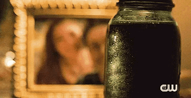 a picture of a couple in a frame next to a jar with a cw logo on it