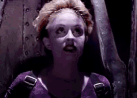 a woman in a purple shirt is standing in a dark room