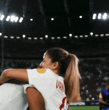 a woman wearing a white jersey with the word van on the back is hugging another woman