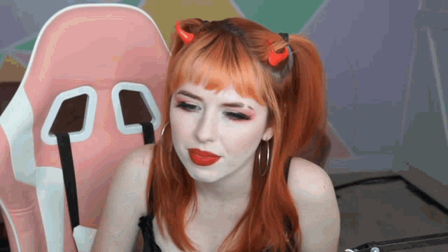 a woman with red hair is wearing devil horns on her head