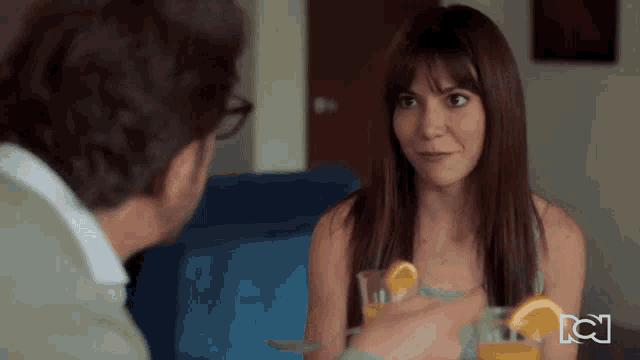 a woman sitting at a table with a glass of orange juice and a sign that says tc
