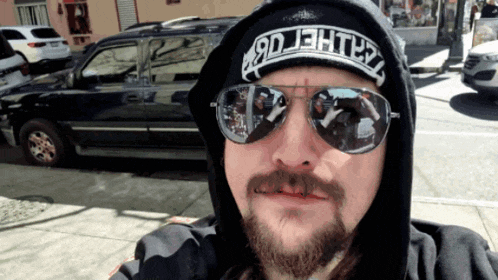 a man with a beard wearing sunglasses and a hat that says 9djht3l