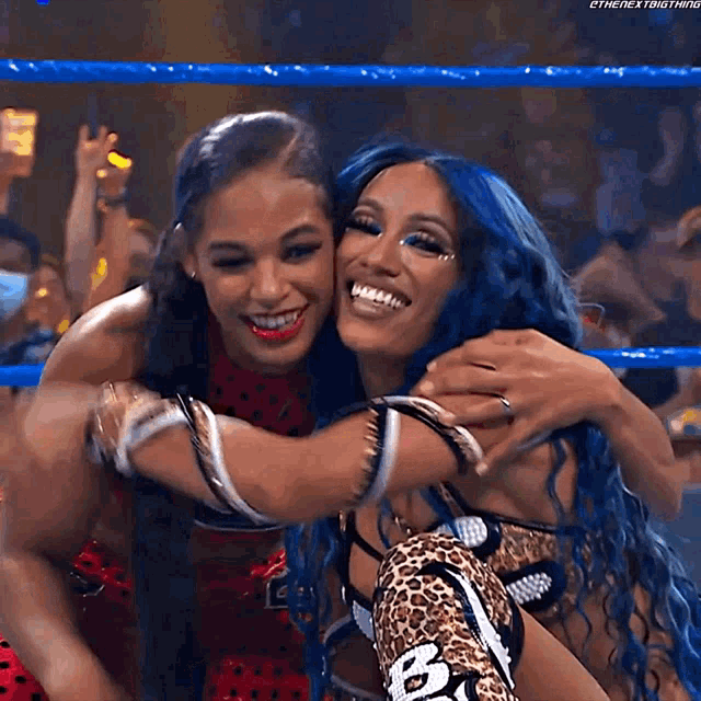 two female wrestlers are hugging each other in a wrestling ring .