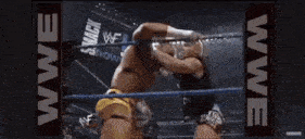 two men are wrestling in a wrestling ring and one of them is wearing a yellow belt .