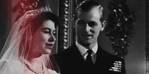 a black and white photo of a bride and groom standing next to each other .