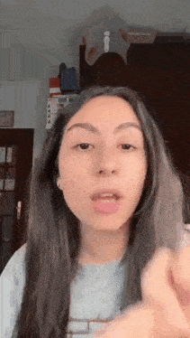 a young woman with long hair is making a funny face while talking into a microphone .
