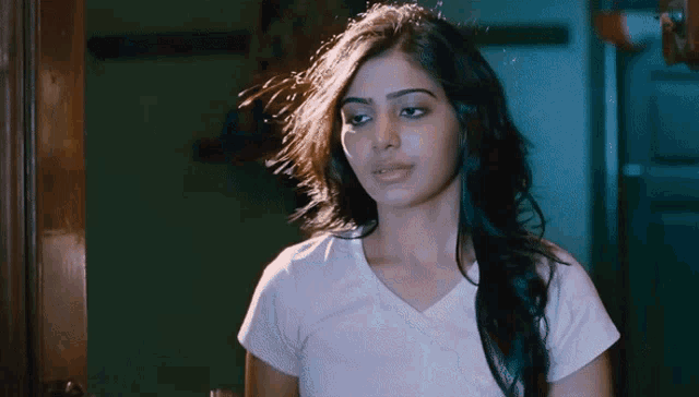 a woman in a white t-shirt looks at the camera