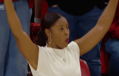 a woman sitting in a stadium with her arms in the air and a sign that says espn in the background