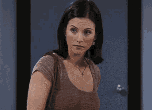 a woman standing in front of a door wearing a necklace