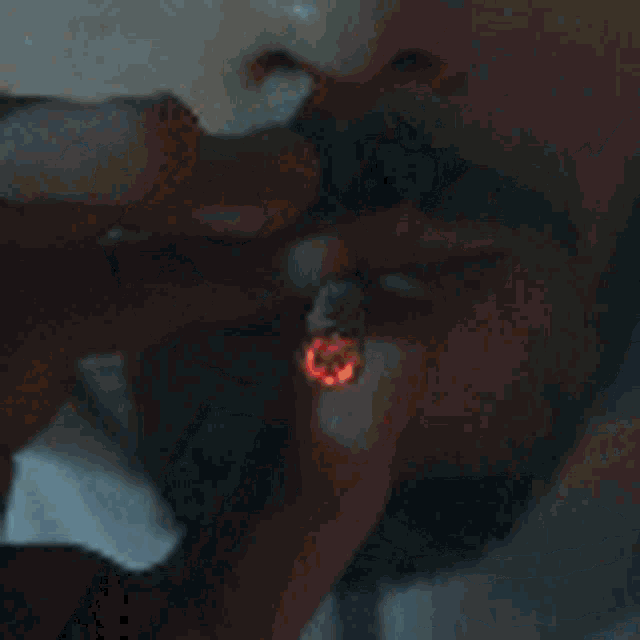 a close up of a man 's face with a beard and mustache smoking a cigarette .