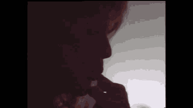 a close up of a person 's face in the dark with a hand on their chin .