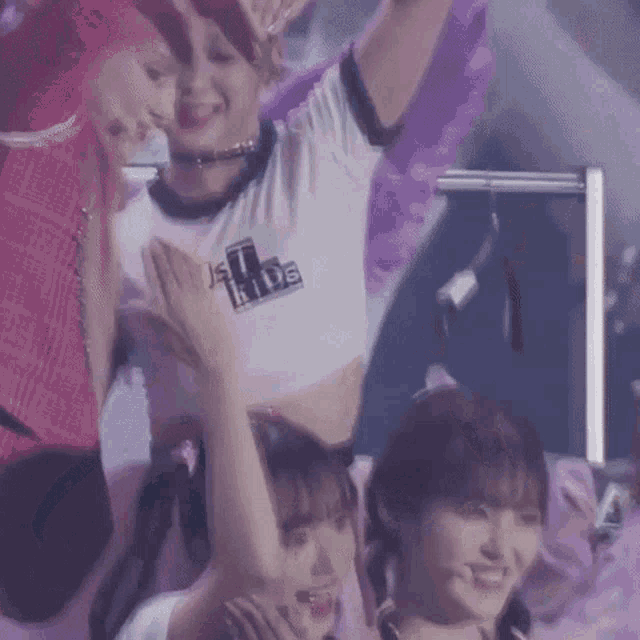 a group of young women are standing next to each other on a stage with their arms in the air .