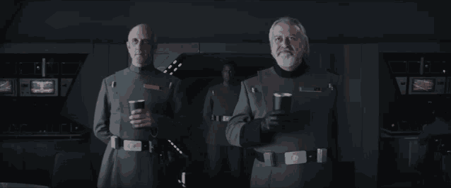 two men in military uniforms are standing next to each other holding cups of coffee