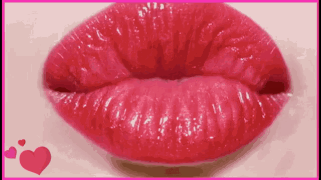 a close up of a woman 's red lips with a pink heart in the background