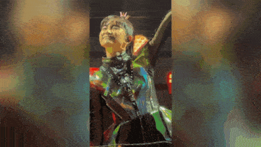 a woman with a crown on her head is standing on a stage with her arms outstretched