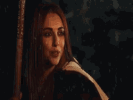 a woman with long red hair is holding a sword in her hand .