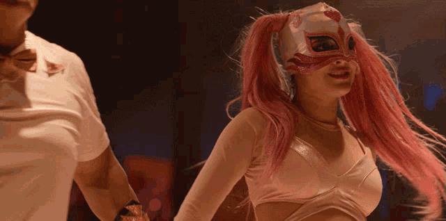 a woman with pink hair is wearing a mask and holding hands with a man