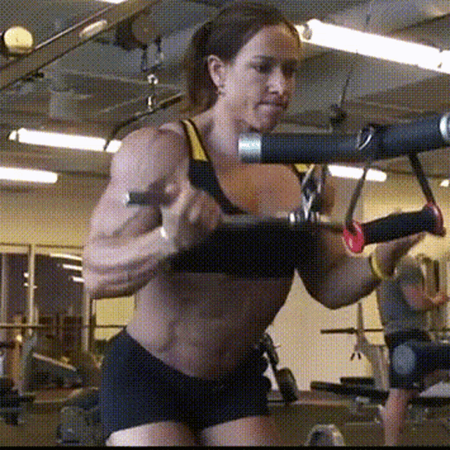 a woman is lifting a machine in a gym