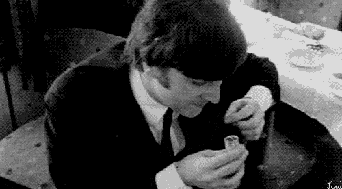 a man in a suit and tie is sitting at a table holding a lighter .