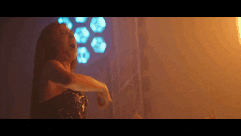a woman in a black dress is dancing in front of a window