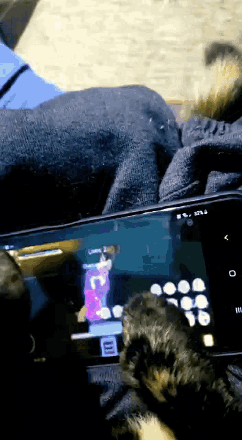 a cat 's paw rests on a cell phone with a cartoon on the screen